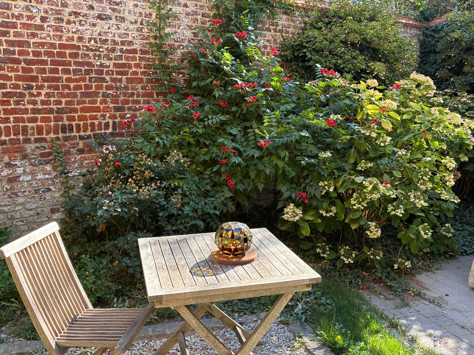 Sphère en vitrail posée sur une table de jardin, derrière l'atelier